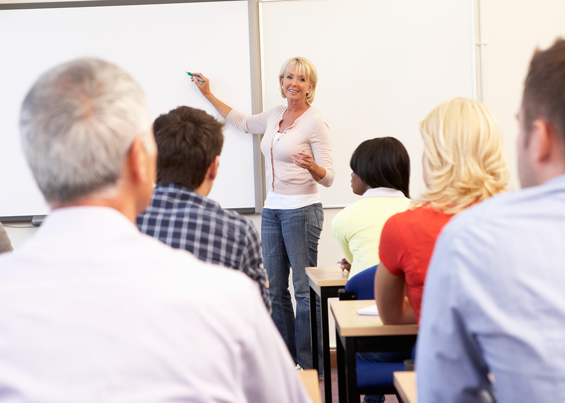 Woman standing at a blackboard in the front of a classroom